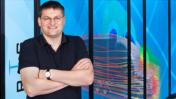 Photo of Michael Resch in front of supercomputer.
