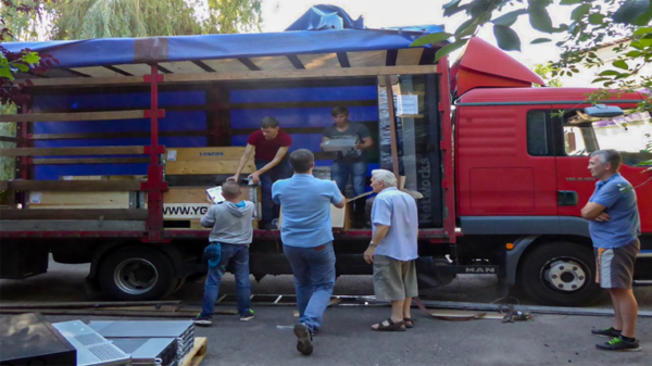 Several people unload crates from a truck.