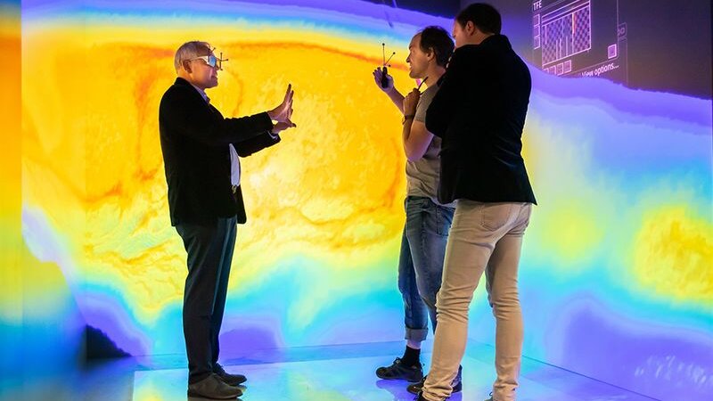Three people observing a visualization in the CAVE.