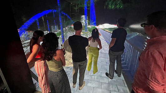 Photo of several people observing a model of a bridge in virtual reality.
