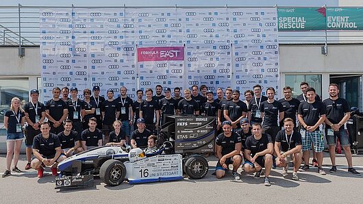 Photo of racing team with their Formula 1 style car.