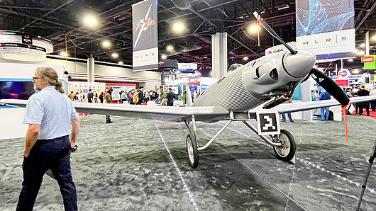 A man walks past an antique-looking airplane on the HLRS convention stand.