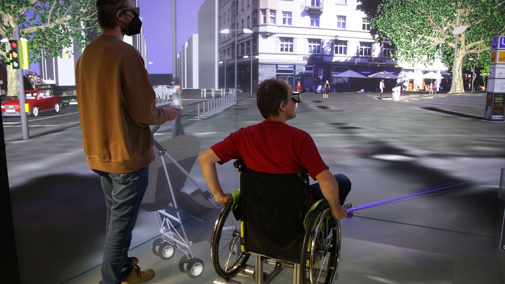 Foto aus der Visualisierungsanlage CAVE, das zwei Personen auf dem Marienplatz in Stuttgart zeigt. Eine Person davon steht, die andere sitzt im Rollstuhl.