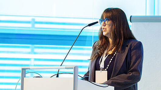 A woman gives a speech at a podium.