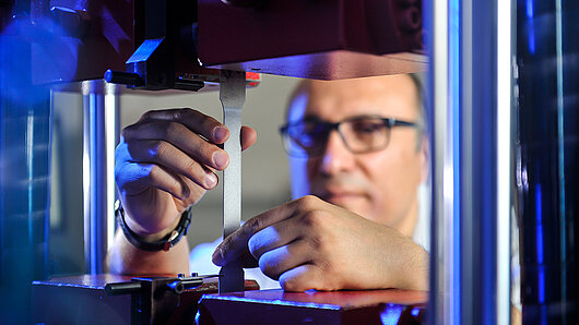 Foto von Dr. Celalettin Karadogan, der ein Experiment beobachtet, bei dem ein dünnes Stück Metall getestet wird.