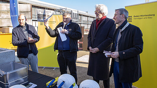 Gegenstände werden in die Zeitkapsel im Grundstein gelegt. Michael Resch hält eine Ausgabe der Stuttgarter Zeitung vom selben Tag in der Hand.