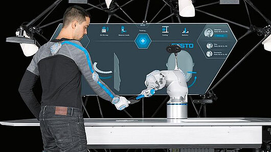 Photo of worker alongside robotic arm
