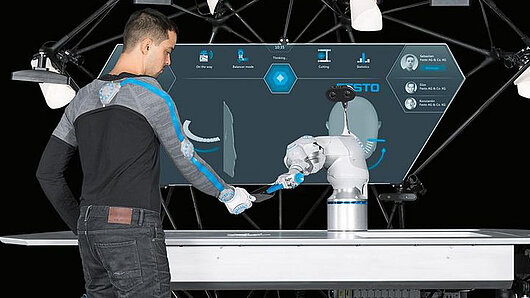 Photo of worker alongside robotic arm