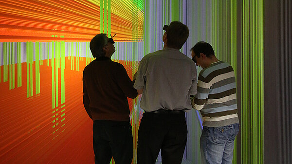 Three men discuss a 3D visualization.