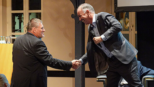 Two men shaking hands and laughing