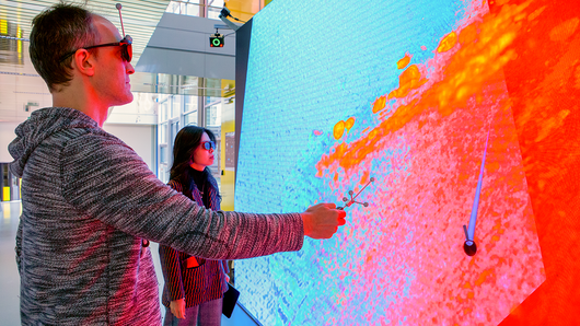 Foto von zwei Personen, die mit einer digitalen Wand interagieren