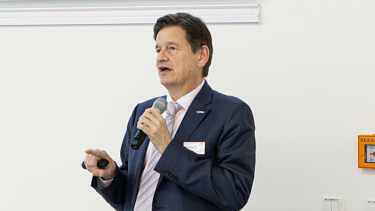 A man holds a microphone while giving a speech.