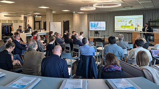 Photo of conference room with audience watching a presentation.