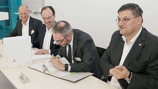 HPE executives and representatives of the University of Stuttgart sitting at a table during the signing ceremony.
