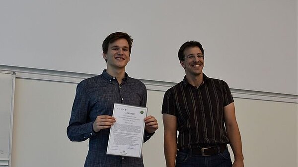 Niklas Knöll (left) receives Simulated Worlds certificate from HLRS employee Ralf Schneider. (Photo: HLRS)