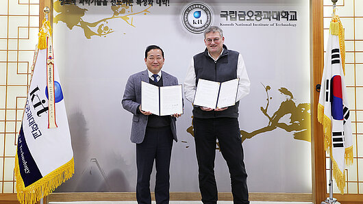  Ho Sang Kwak and Michael Resch hold copies of the signed agreement.