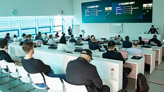 Foto des HLRS-Auditoriums während des Future Computing Workshops. Auf einer Leinwand vorne im Saal steht „A Paradigm Shift“