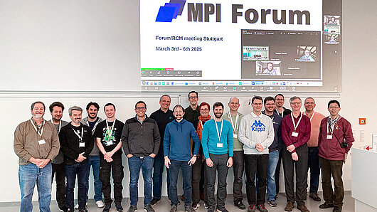 Group photo of MPI Forum participants in the HLRS auditorium, with MPI Forum logo and online attendees on screen behind them.