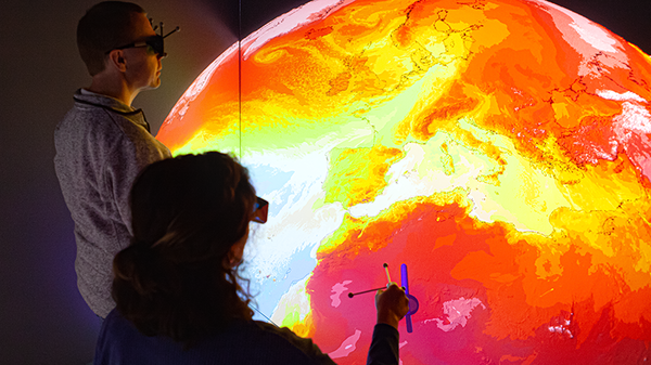 Second view of two scientists observe a visualization of global weather.