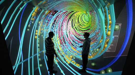 Photo of HLRS's CAVE showing two people inside computer visualization of spiraling flow