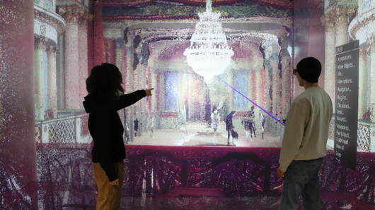 Photograph of two people observing a 3D visualization of a theater.