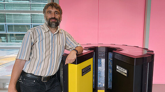 Dr. Thomas Bönisch stands in front of the Cray2 supercomputer in the HLRS foyer.