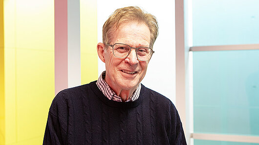 Photo portrait of Steve Conway, with geometric pattern in background.