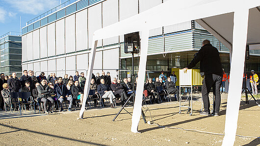 Foto des Redners und des Publikums bei der Veranstaltung, aufgenommen hinter dem Redner.