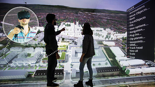 Photo of scientists oberving aerial visualization of city. in an inset, another wears a VR headset.