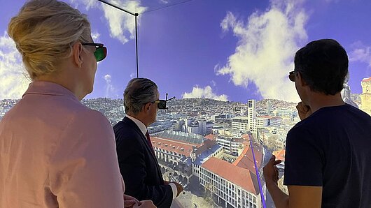 Ines Aufrecht, Frank Nopper, and Uwe Wössner observe a digital twin of downtown Stuttgart in the HLRS CAVE.