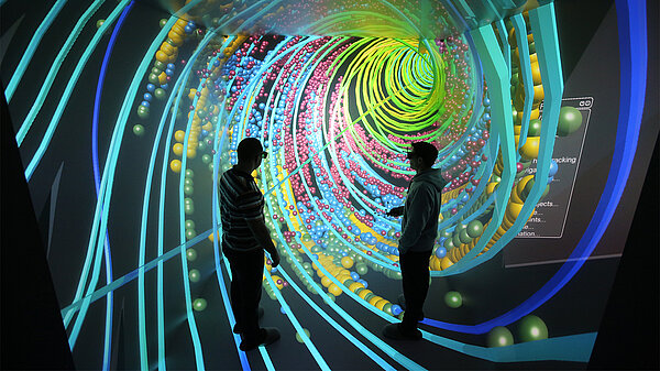 Two researchers observe a simulation of a spiraling flow of particles.