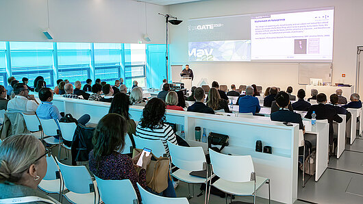 Photograph of many people in the HLRS auditorium. A man speaks at the podium.