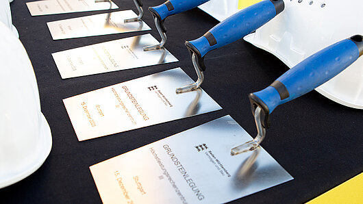 Auf einem Tisch liegen Gedenkkellen.