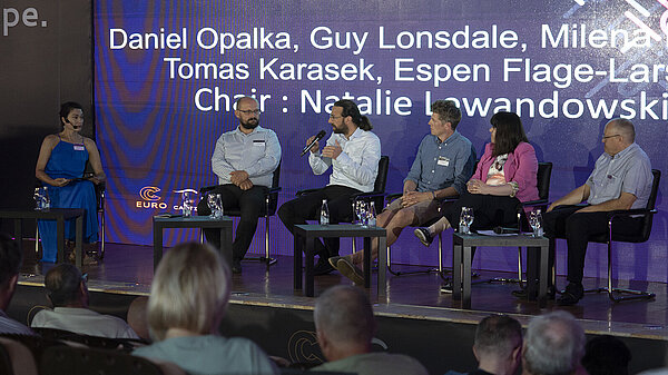 Panel of speakers on stage at EuroCC conference.