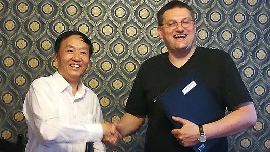 Director of the Shanghai Supercomputing Center Ximin Zhou and HLRS Director Michael Resch shake hands to celebrate collaboration agreement.