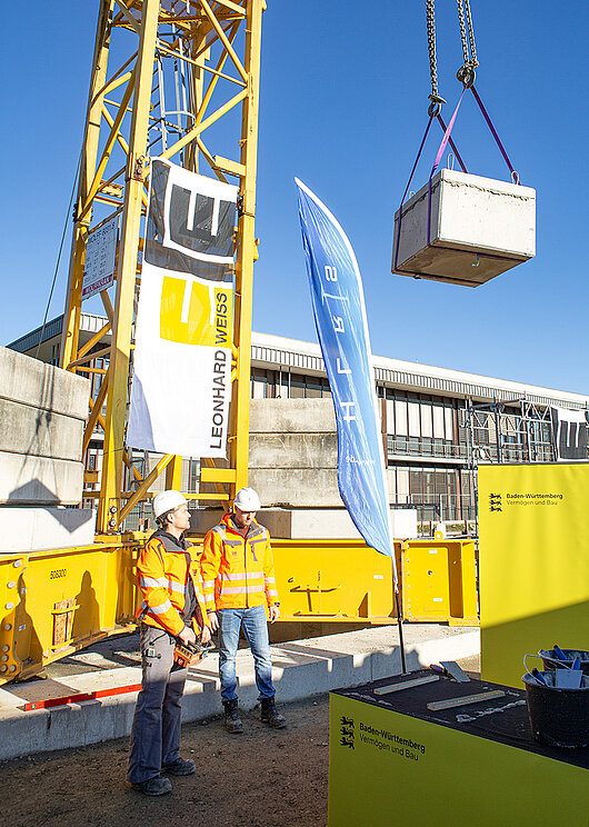 A crane hoists the cornerstone into the construction site.