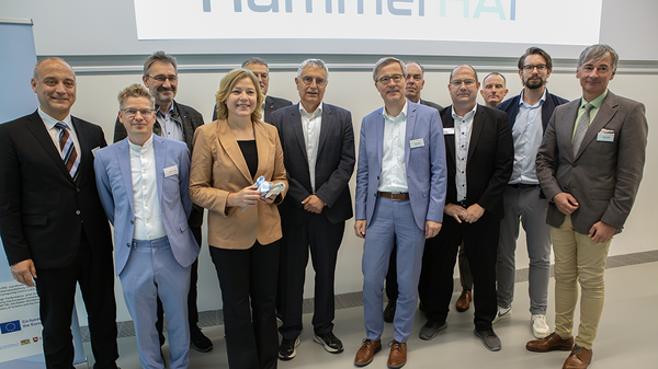 Group portrait photo in front of a screen with the name HammerHAI on it.